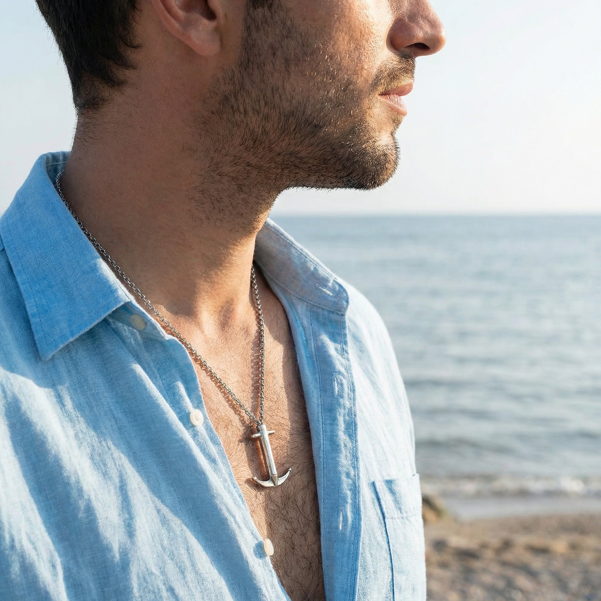 Man standing on a beach looking out to sea wearing Anchor & Crew Admiral Anchor sterling silver necklace.