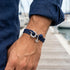 Man wearing Anchor & Crew Clyde sterling silver navy blue rope bracelet on wrist.