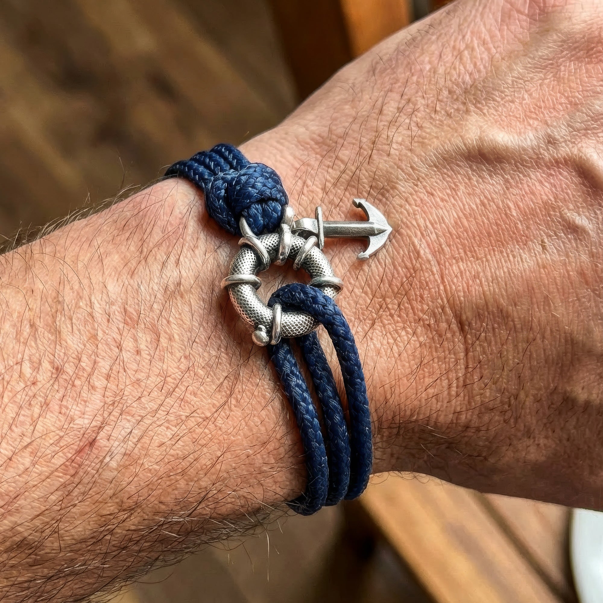 Close-up of man wearing Anchor & Crew Clyde sterling silver navy blue rope bracelet on wrist.
