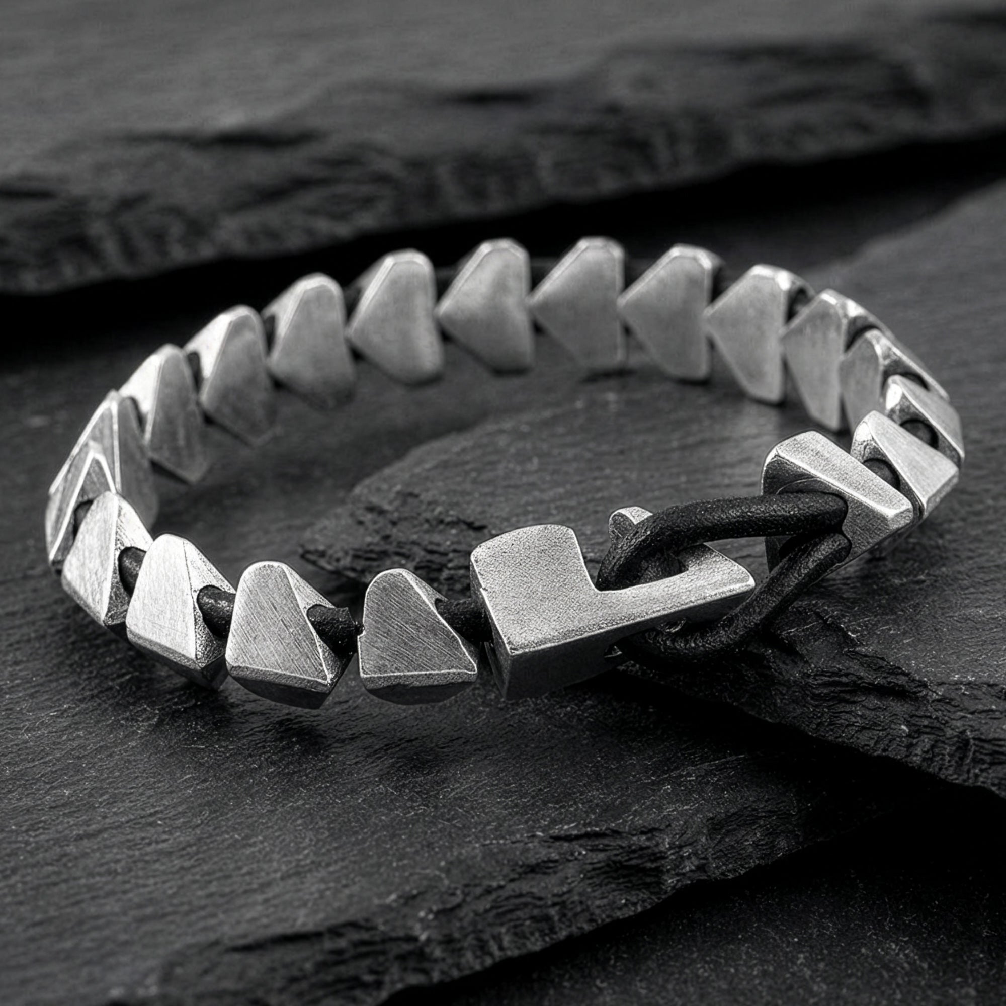 Anchor & Crew Brixham sterling silver & black leather bracelet on black slate surface.
