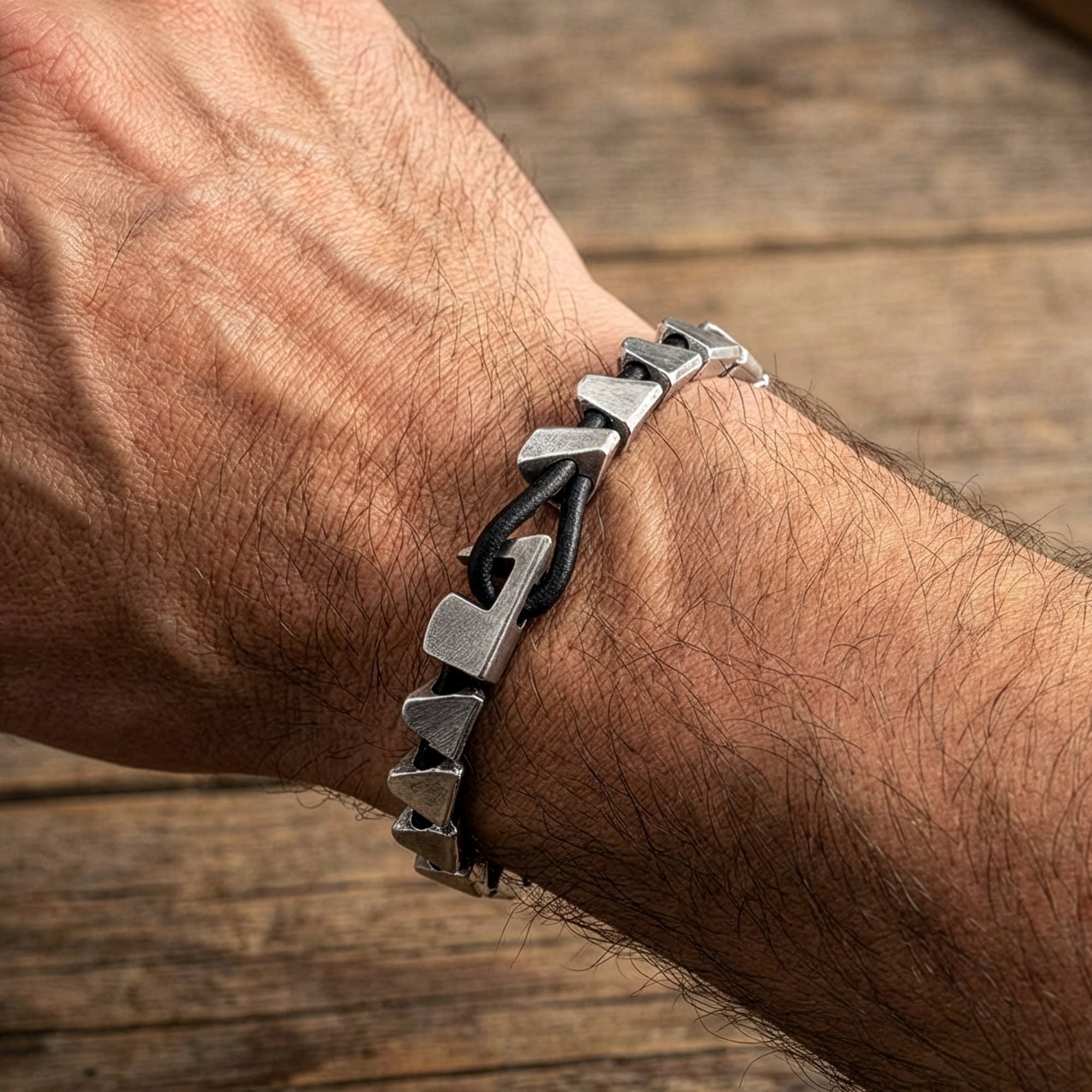 Close-up of man wearing Anchor & Crew Brixham sterling silver & black leather bracelet on his wrist.