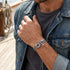 Man wearing Anchor & Crew Clyde sterling silver grey rope bracelet on the deck of an old sailing ship.