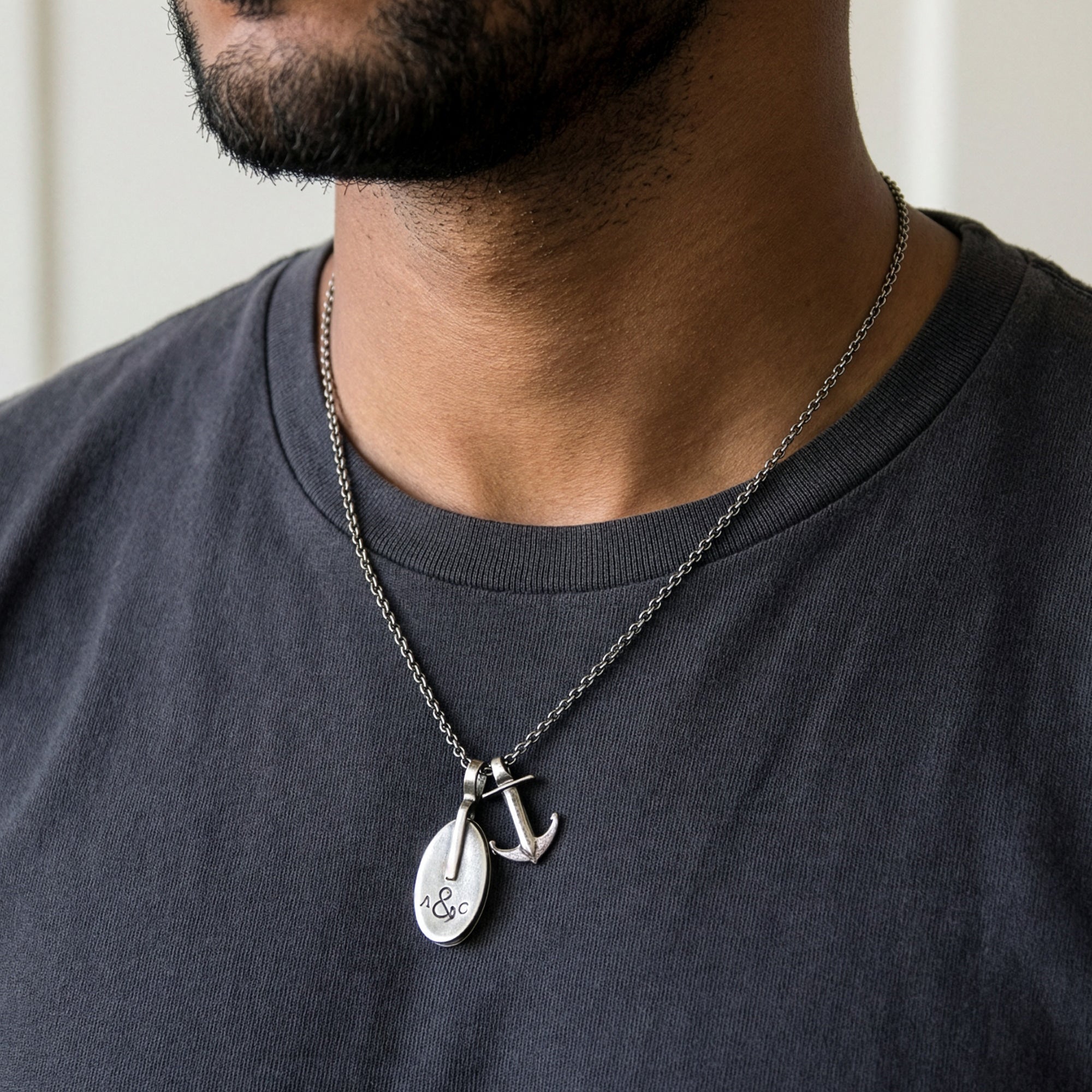 Close-up of a man in a t-shirt wearing an Anchor & Crew London pulley & anchor sterling silver necklace.