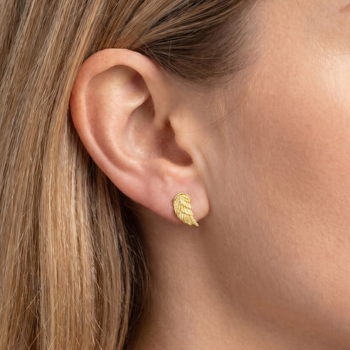 Woman wearing Engelsrufer angel wing gold stud earrings.