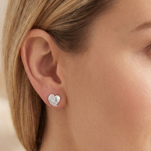 Woman wearing Engelsrufer angel wing heart silver CZ stud earrings.
