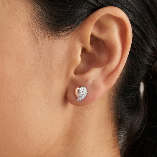 Woman wearing Engelsrufer angel wing heart rose gold silver CZ stud earrings.