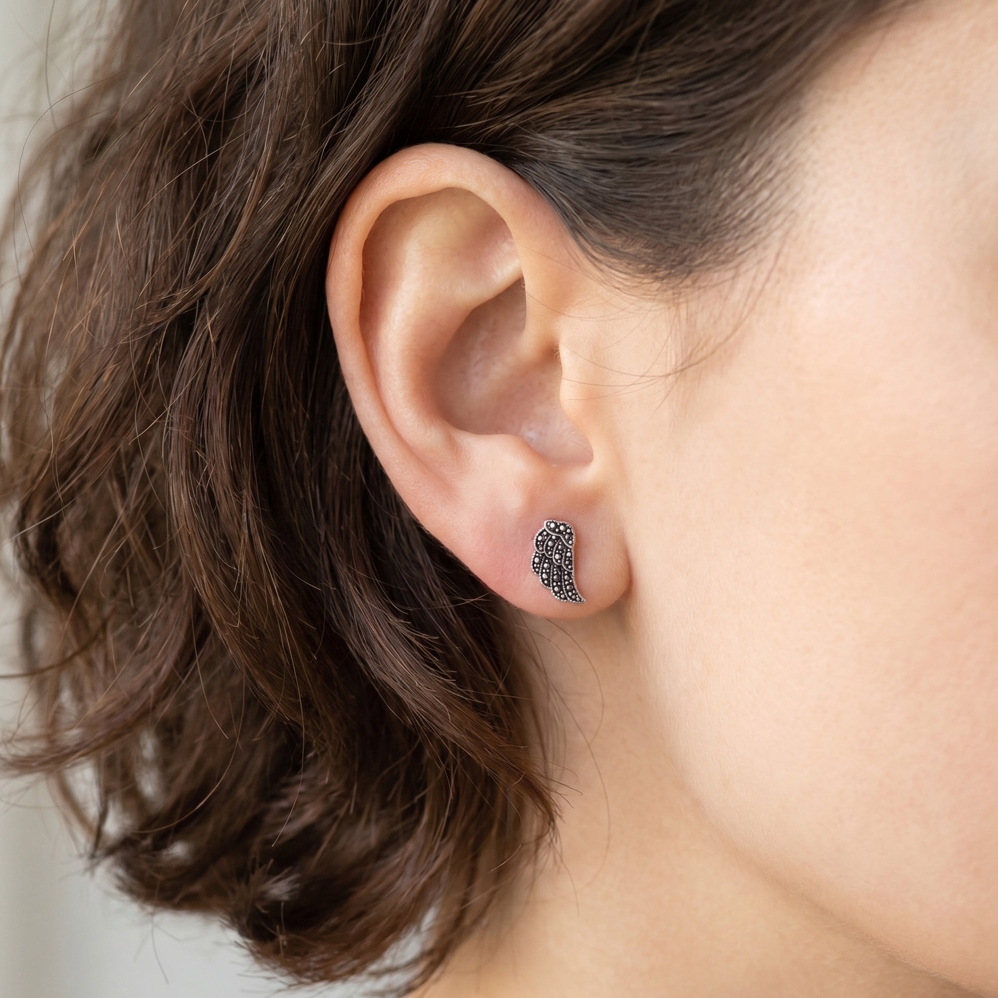 Woman wearing Engelsrufer little angel wing marcasite silver CZ stud earrings.