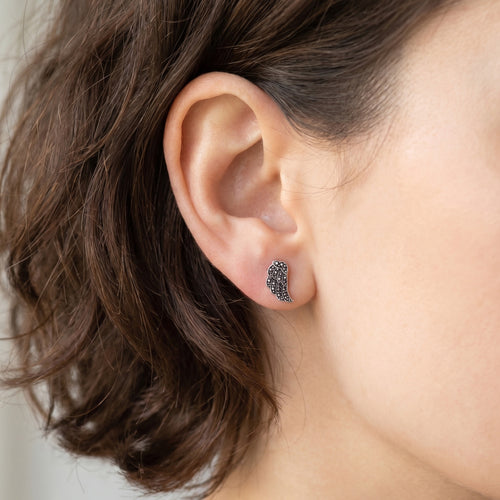 Woman wearing Engelsrufer little angel wing marcasite silver CZ stud earrings.