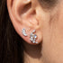 Close-up of woman wearing Engelsrufer angel wing & moon mismatch stud earrings.