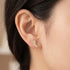 Woman wearing Engelsrufer angel wing crystal pave gold stud earrings.
