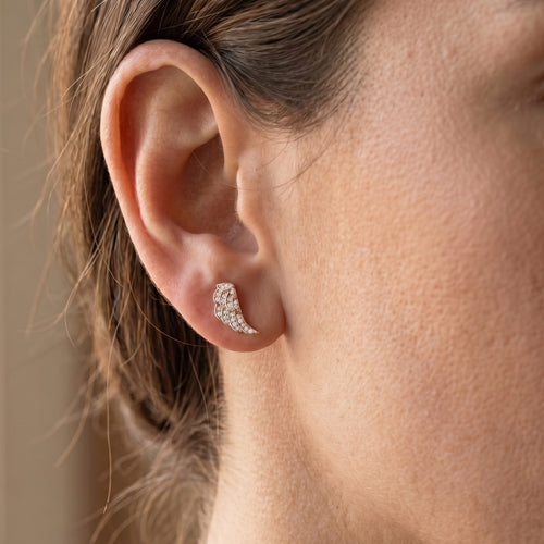 Woman wearing Engelsrufer angel wing crystal pave rose gold stud earrings.