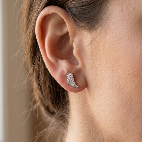 Woman wearing Engelsrufer angel wing crystal pave sterling silver stud earrings.