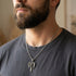 Man wearing an Archangel Michael sword silver necklace looking to the left.