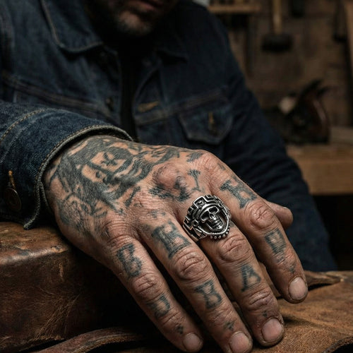 Man in denim jacket with hand tattoos wearing stainless steel men's skull Aztec death mask ring.