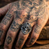 Stainless steel men's skull Aztec death mask ring on man's tattooed hand.