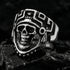 Stainless steel men's skull Aztec death mask ring sitting on black molten obsidian rock.