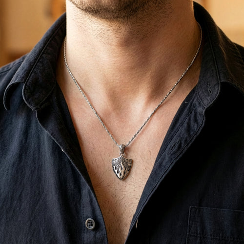 Man in an open-neck shirt wearing a battle flames shield stainless steel necklace.