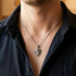 Man in an open-neck shirt wearing a battle flames shield stainless steel necklace.