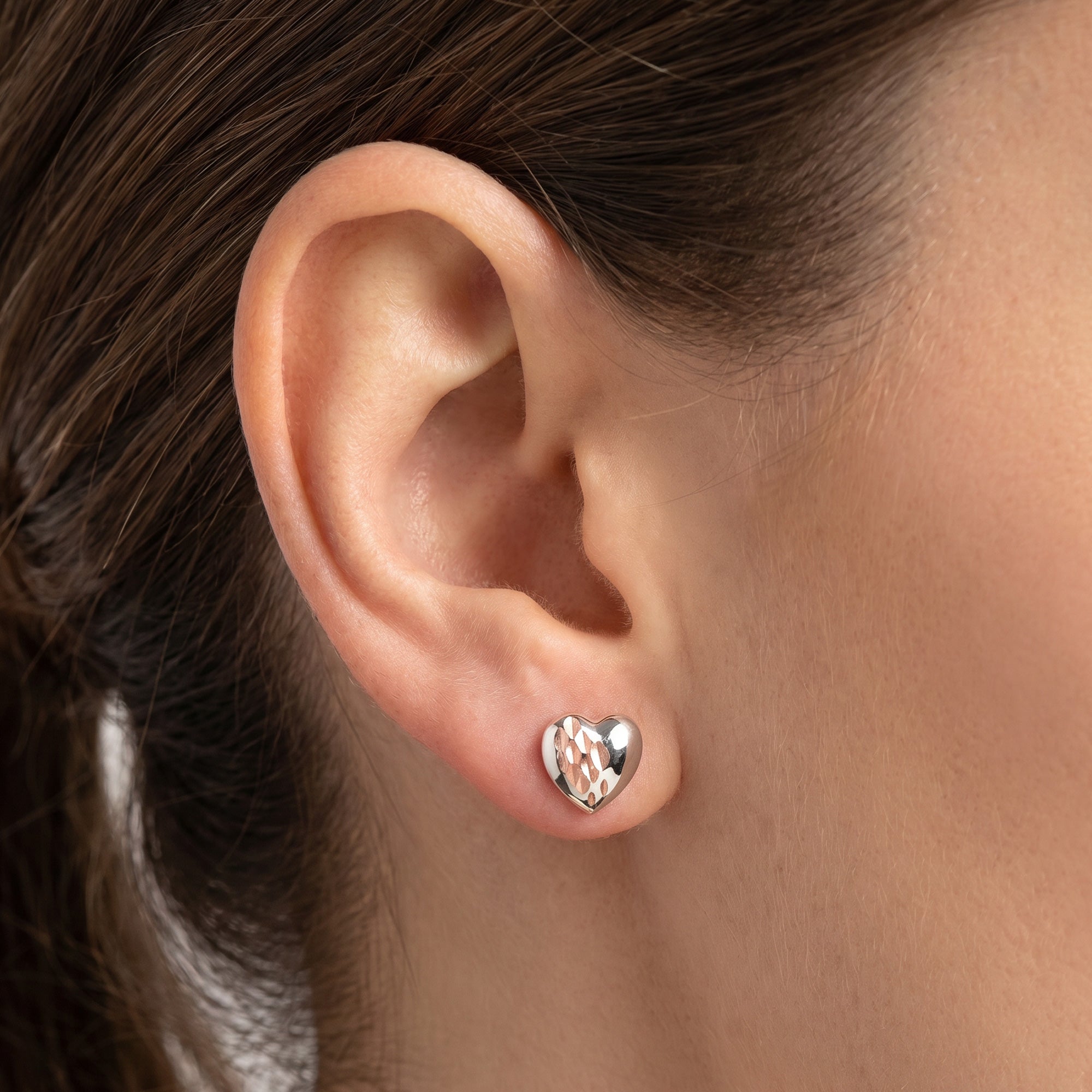 Woman wearing Engelsrufer  beating love heart silver rose gold stud earrings.