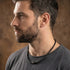 Man looking left wearing Save Brave black braided leather men's bead necklace.