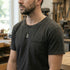 Man standing in a woodworking workshop wearing black steel men's cross dog tag necklace.