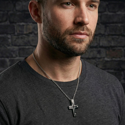 Close-up of man wearing black rivet cross stainless steel necklace.