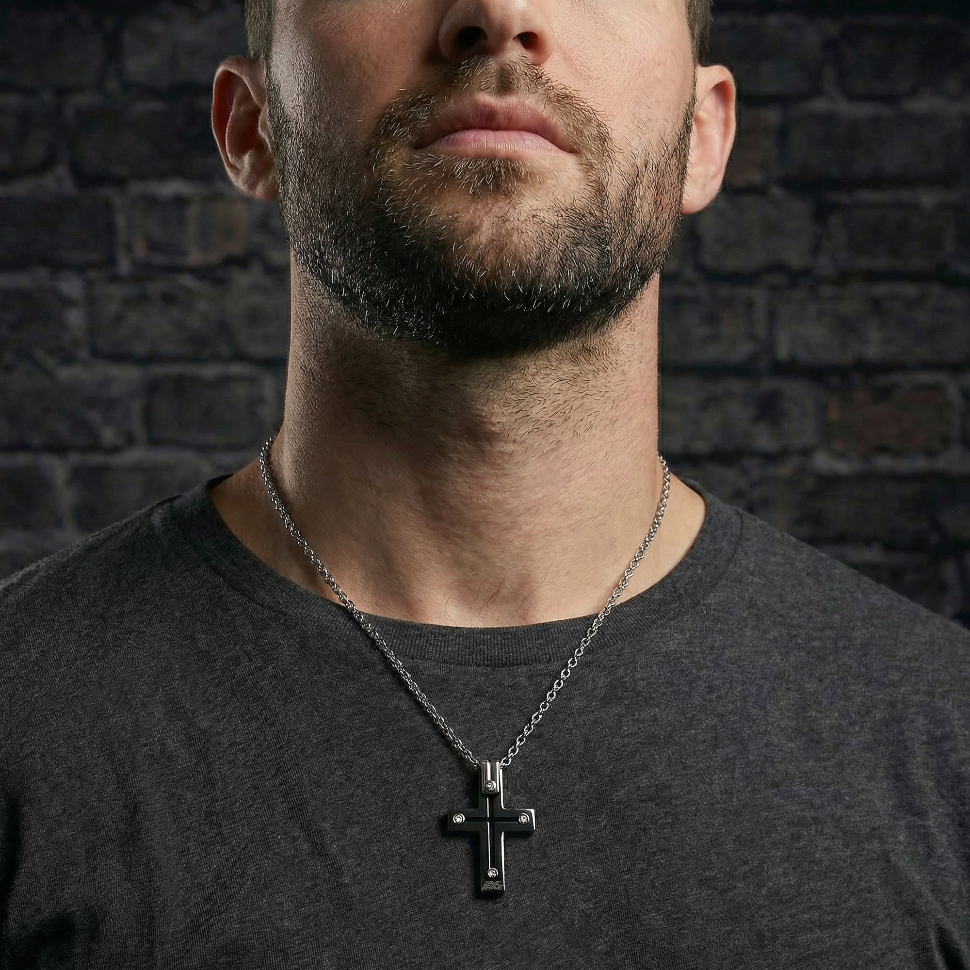 Man in grey t-shirt wearing black rivet cross stainless steel necklace.
