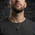 Man in grey t-shirt wearing black rivet cross stainless steel necklace.