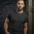 Man leaning against steel girder wearing black rivet cross stainless steel necklace.