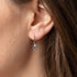 Close-up of a woman wearing Engelsrufer aqua blue CZ hoop dangle earrings.