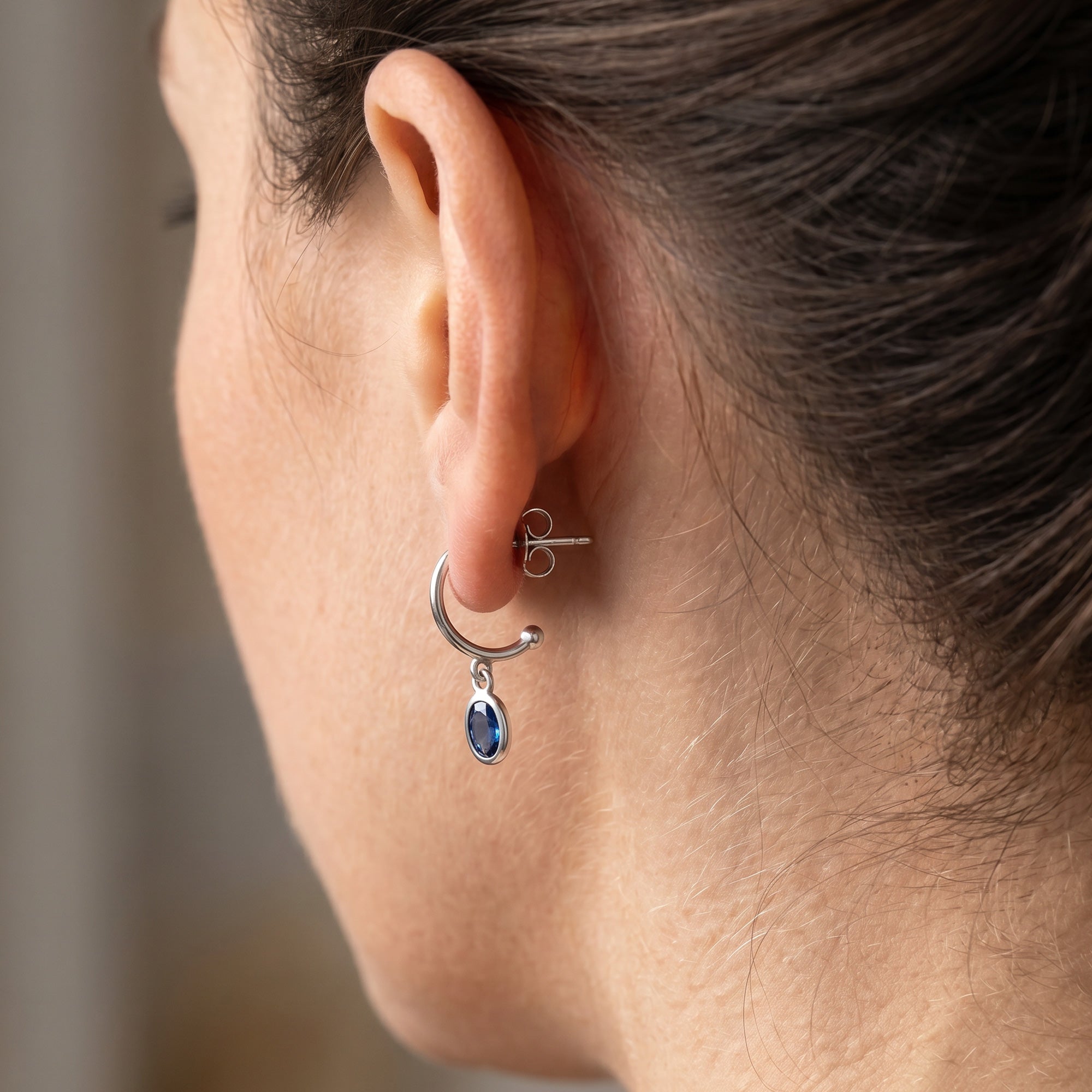 Side view of a woman wearing Engelsrufer aqua blue CZ hoop dangle earrings.