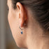 Side view of a woman wearing Engelsrufer aqua blue CZ hoop dangle earrings.