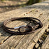 Anchor & Crew Dundee sterling silver dark brown braided leather bracelet on log outdoors.