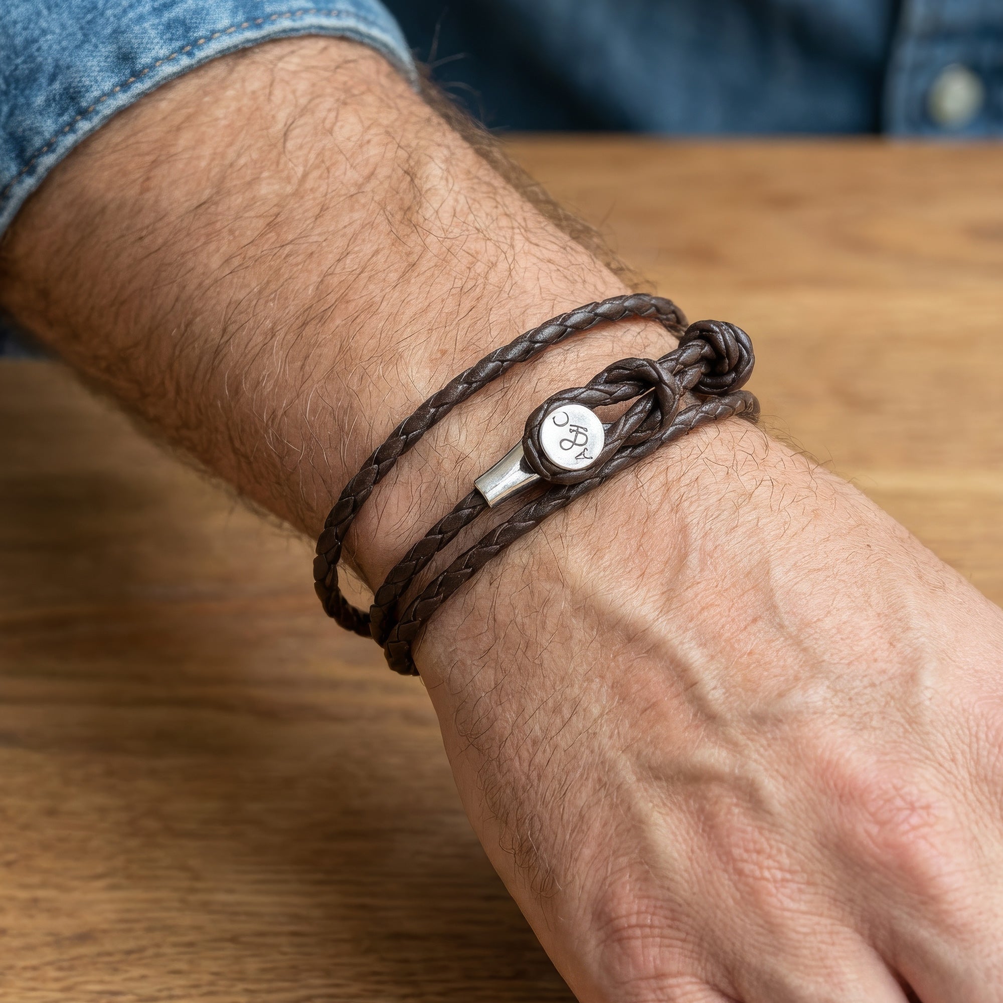 Close-up of Anchor & Crew Dundee sterling silver dark brown braided leather bracelet on a man's wrist.