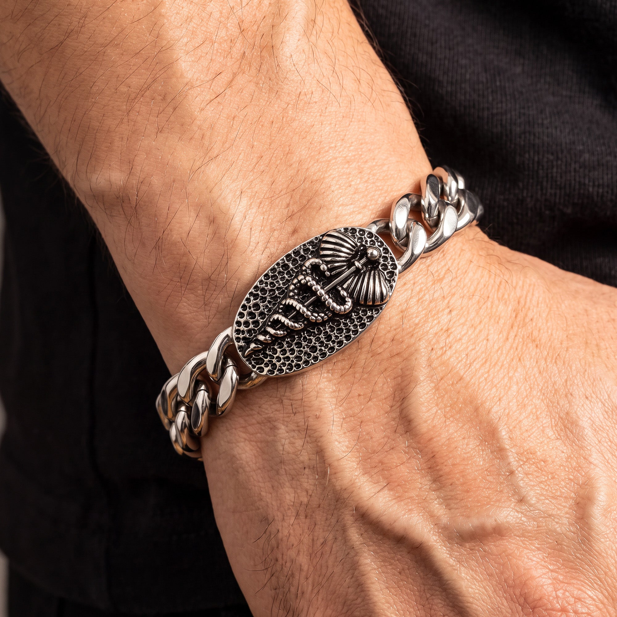 Close-up of a man's wrist wearing a caduceus Cuban link men's stainless steel bracelet.
