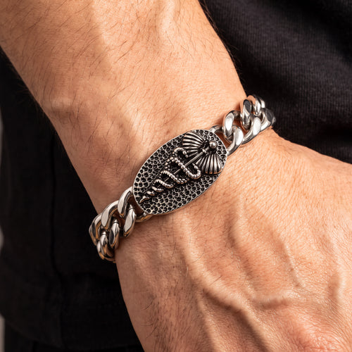 Close-up of a man's wrist wearing a caduceus Cuban link men's stainless steel bracelet.