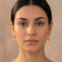 Woman wearing a pair of Engelsrufer cage ball gold hook earrings.