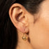 Woman wearing Engelsrufer cage ball gold hook earrings.
