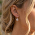 Close-up of a woman wearing Engelsrufer cage ball silver hook earrings.