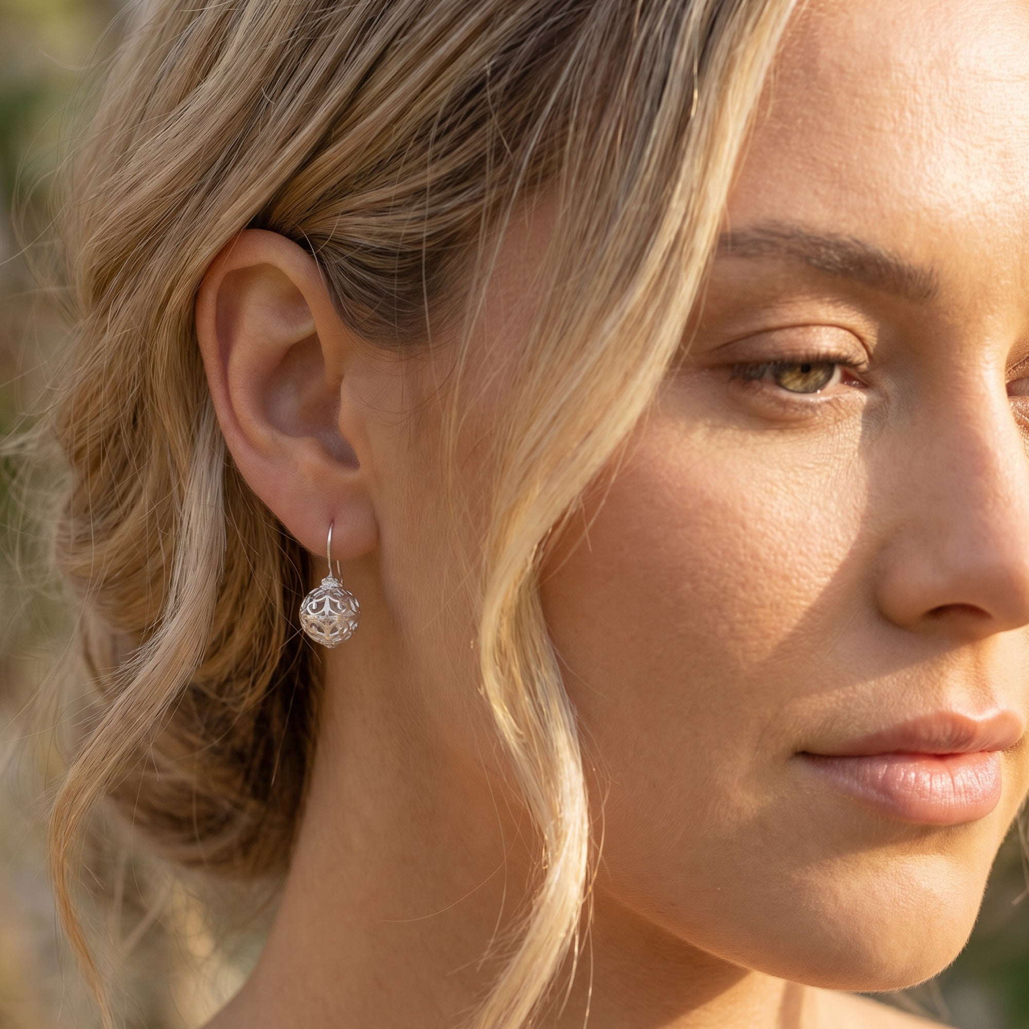 Woman wearing Engelsrufer cage ball silver hook earrings.
