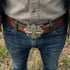 Downward close-up of a man's waist wearing a belt with a Celtic green man face belt buckle.