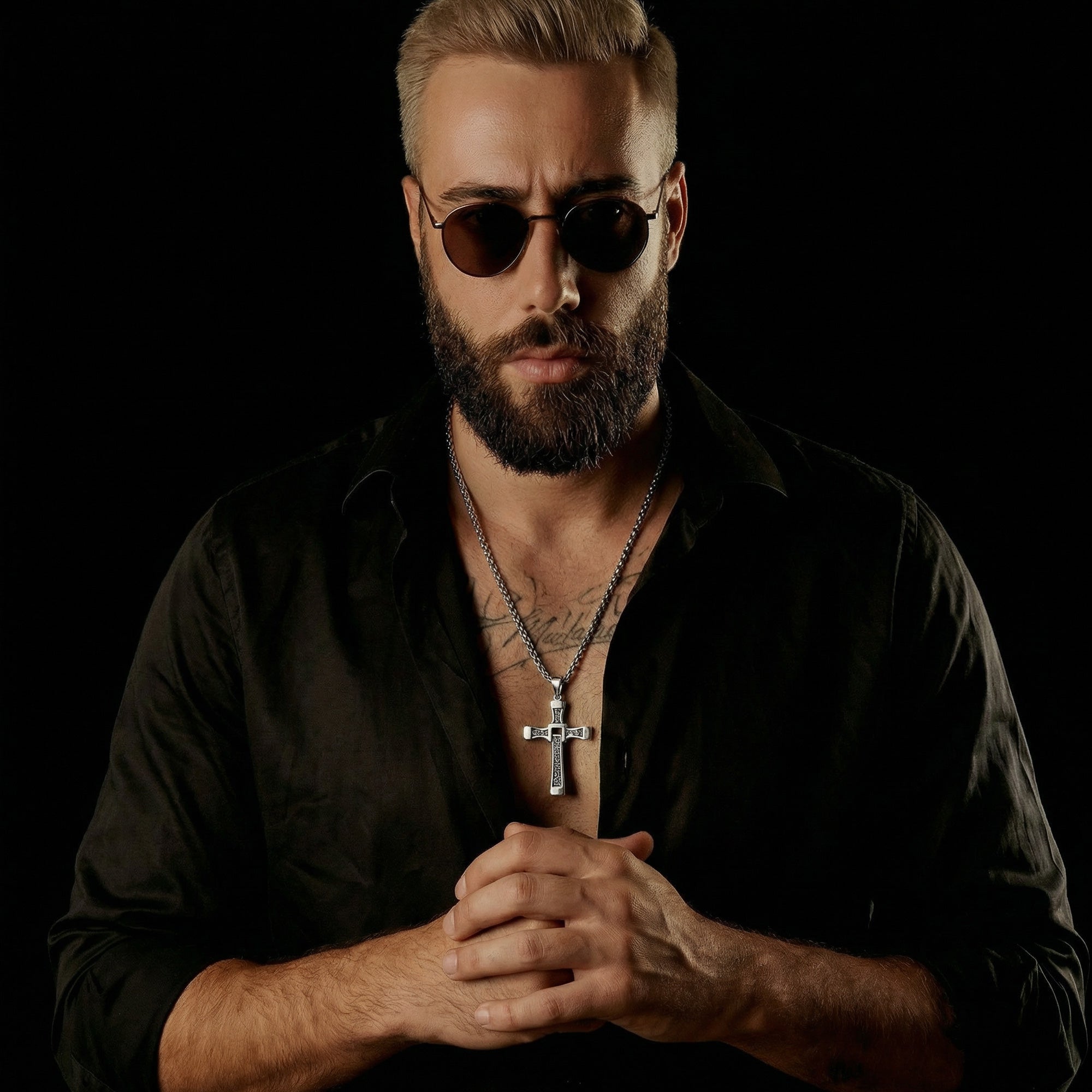 Beared man in sunglasses with hands clasped wearing celtic runes swivel cross stainless steel necklace.