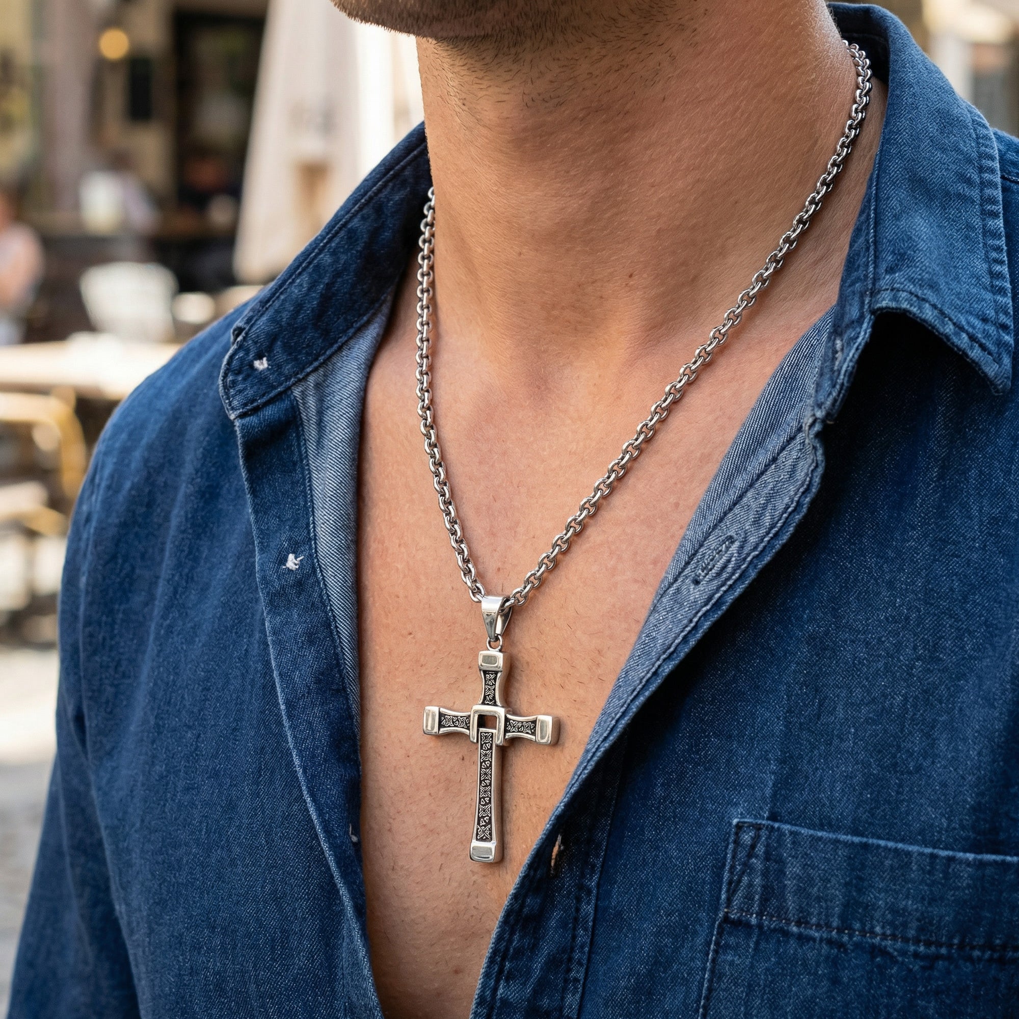 Close up of man in blue denim shirt wearing celtic runes swivel cross necklace.
