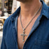 Close up of man in blue denim shirt wearing celtic runes swivel cross necklace.