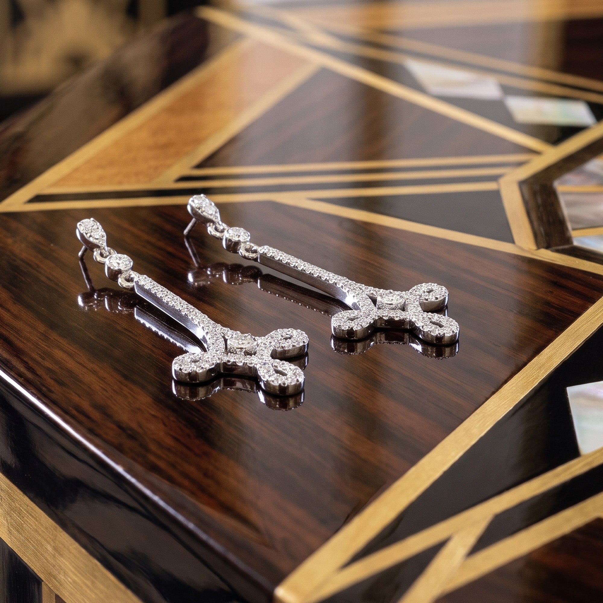 A pair of chandelier scroll Art Deco pave CZ dangle earrings on a polished wood inlay table.