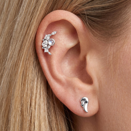 Close-up go woman wearing Engelsrufer cherub angel wing & moon mismatch earrings.