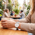 Woman wearing Cluse La Boheme rose gold white/pastel baby blue watch at an outdoor restaurant.