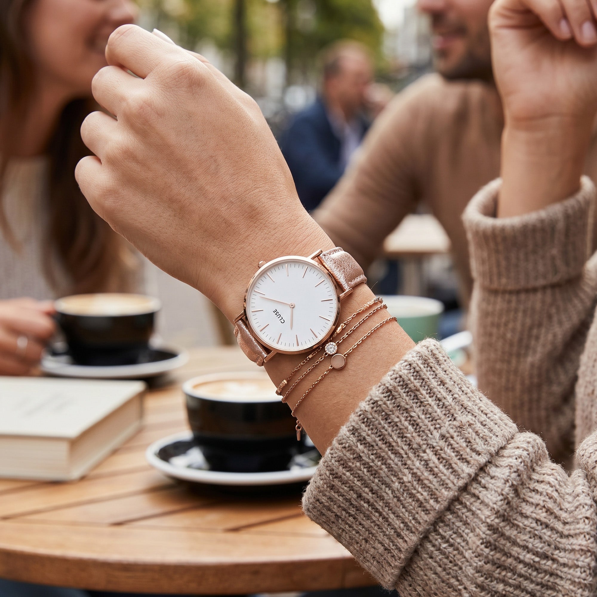 Woman wearing Cluse La Boheme rose gold white/rose gold metallic watch at a social gathering.