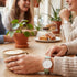 Woman wearing Cluse La Boheme rose gold white/pastel mint green watch at a social gathering.