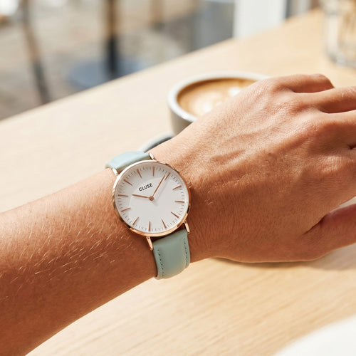 Woman wearing Cluse La Boheme rose gold white/pastel mint green watch.